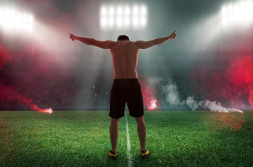 Fototapeta na wymiar Fußballer mit nackten Oberkörper verneigt sich nach gewonnenen Spiel vor der Tribüne