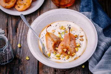 Healthy breakfast bowl: yogurt with caramelized pears, pistachios, honey and chia seeds