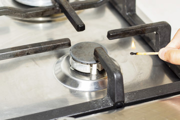 A man lighting the gas-stove with a match