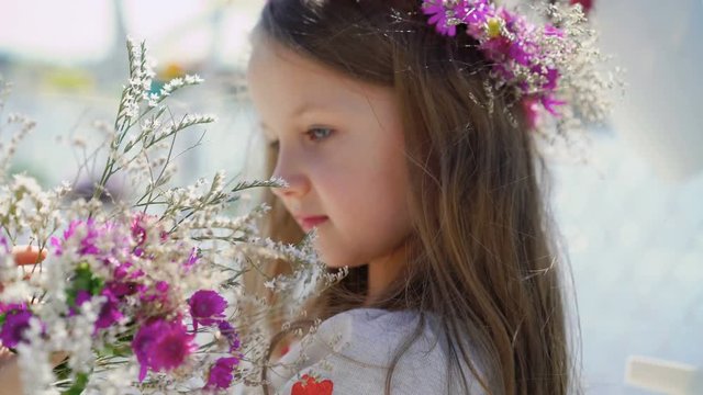 Little amazing girl with blue eyes playing with bouquet of flowers. 4K