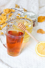 Closeup of cup of tea with tea leaves, mint on vintage wooden background. Black herbal tea with lemon, ginger and honey. hot winter drink