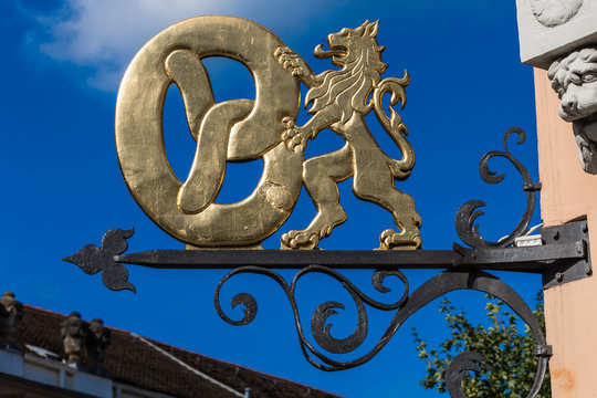 Historisches vergoldetes Zunftzeichen an einer B&auml;ckerei, L&ouml;we mit Brezel