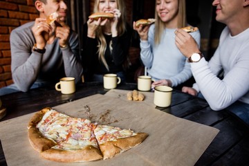 young friends sitting in a cafe and eat pizza