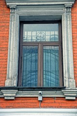 Fototapeta na wymiar Старое окно с решёткой на кирпичной стене жилого дома