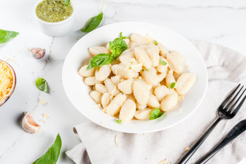 Italian food recipe, Healthy vegan dinner with potato gnocchi. With grated parmesan cheese, basil and pesto sauce. On white marble , copy space