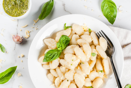 Italian food recipe, Healthy vegan dinner with potato gnocchi. With grated parmesan cheese, basil and pesto sauce. On white marble , copy space  top view