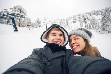 Fototapeta na wymiar Happy boyfriend and girlfriend making selfie on a winter nature