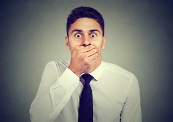 Shocked scared young man covering his mouth with his hand