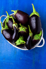 Fresh eggplant in grey basket on blue wooden table.Rustic background. Top view. Copy space. Vegan vegetable.