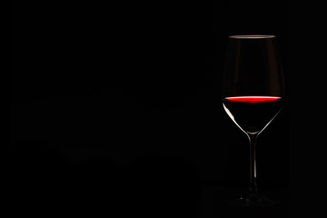 Glas mit Rotwein vor schwarzem Hintergrund 