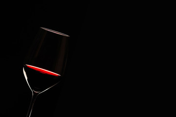 Glas mit Rotwein vor schwarzem Hintergrund 