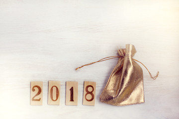 holiday gift wrapping/ Wooden figures denoting 2018 and a golden bag on a light table top view