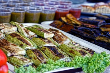 Жареные кабачки и баклажаны на подносе у стаканов с соусом