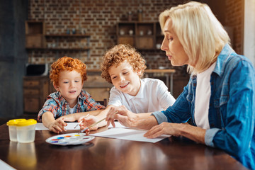 Mindful senior lady painting with grandchildren at home