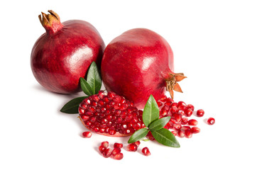 two whole and part of a pomegranate with pomegranate seeds and leaves isolated on white background