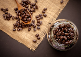 Coffee bean grain in a glass bottle on black table with sack fabric