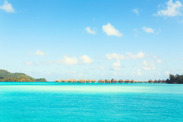 Fototapeta premium Stunning view of blue turquoise lagoon and far bungalows on background of Bora Bora island, French Polynesia