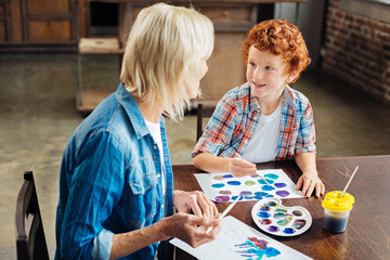 Adorable blue eyed kid gossiping with grandma
