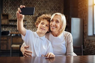 Smiling grandmother and kid taking self portrait with smartphone