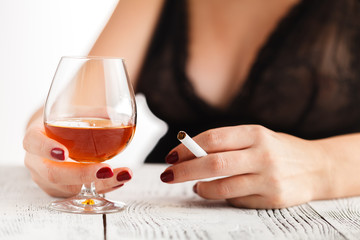 Woman in lingerie sitting at a table and drinking alcohol