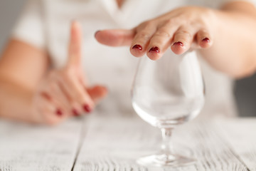 Cropped image of woman showing stop gesture and refusing to drink