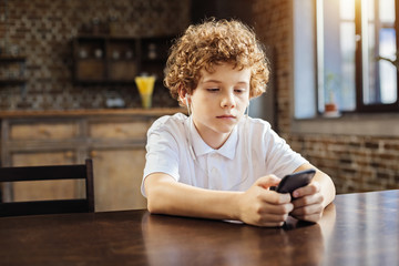 Calm chestnut haired boy choosing music on phone