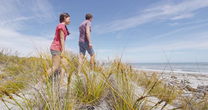Couple walking on beach in New Zealand - people in Ship Creek on West Coast of New Zealand. Tourist couple sightseeing tramping on South Island of New Zealand. SLOW MOTION.