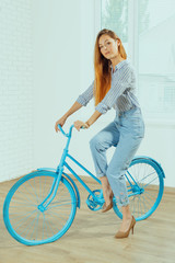 Cheerful young woman standing near bicycle