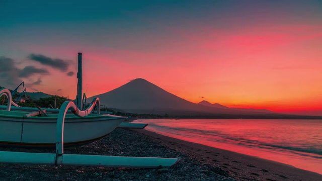 Sunset overlooking the Agung volcano in the background of a fishing boat on the beach of Jemeluk Bay in Amed on the island of Bali in Indonesia.
