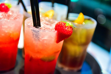 Strawberry cocktails with a strawberry on the edge. Other cocktails and drinks on the tray