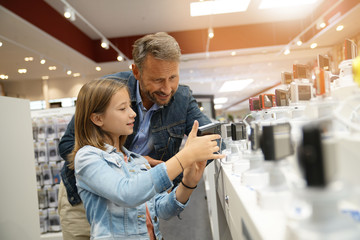 Man with kid looking at compact cameras in multimedia store - obrazy, fototapety, plakaty