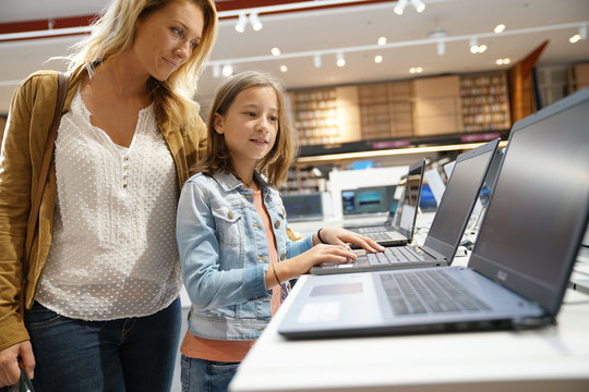 Mother and daughter looking at laptop in multimedia store