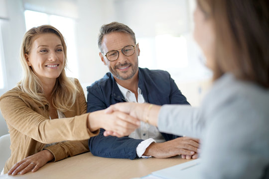 Mature couple meeting real-estate agent in office