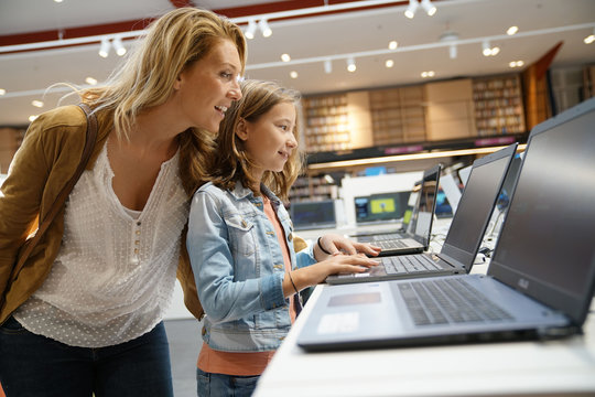 Mother and daughter looking at laptop in multimedia store