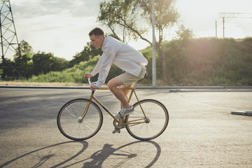 Young handsome hipster man riding fixed gear bicycle during sunset