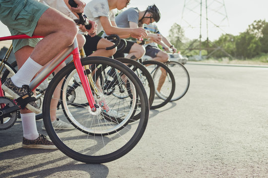 Group of cyclists starting riding fixed gear bikes on the road, close up
