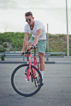 Young handsome hipster man riding fixed gear bicycle during sunset