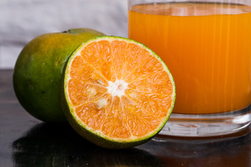 a glass of fresh juice and green mandarins