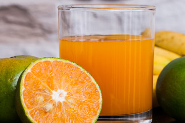 a glass of fresh juice and green mandarins