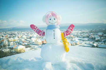 Snowman in pink wig, mittens and scarf.