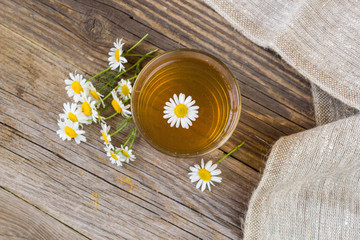 Cup of tea with chamomile flowers on rustic wooden background