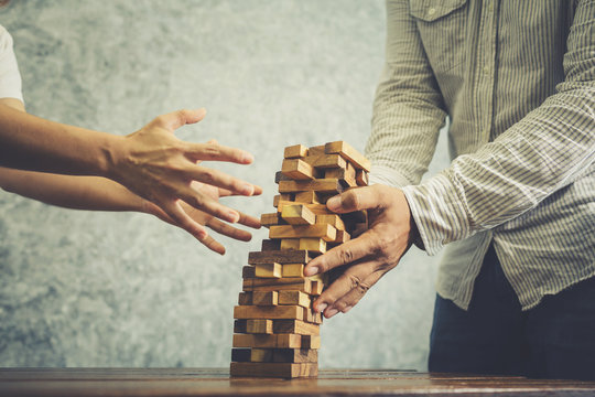 Asian Man And Woman Playing Wood Jenga Game.