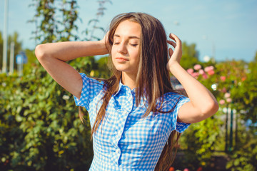 A young sweet woman dressed in a long dress in a blue cage enjoys this day in the garden on a warm sun. Young and beautiful 