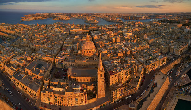 Aerial, panoramic view on historical Three cities over Valletta in golden light. Touristic destination. Historical centre of Malta island from the air. Stone monuments of Malta lit by the setting sun
