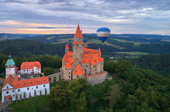 Aerial view on romantic fairytale castle Bouzov with hot air balloon next to highest tower in picturesque czech landscape. Bouzov castle, Moravia, Czech republic.