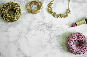 Delicious donuts and cosmetics on the marble table