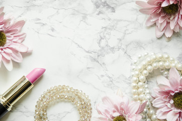 Flowers with feminine accessories lie on a marble background