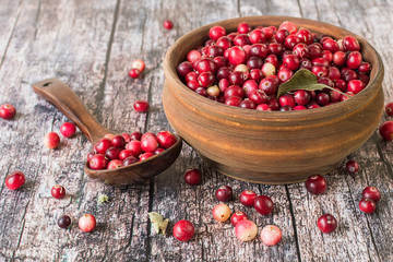   Fresh cranberries in a round wooden bowl on an old table. The source of natural vitamins. Used in folk medicine.