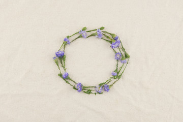 Round wreath of purple cutter flowers on white muslin fabric with copy space