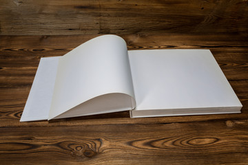 Photo of blank opened brochure magazine on wooden background with soft shadows. Mock-up for graphic designers portfolios.